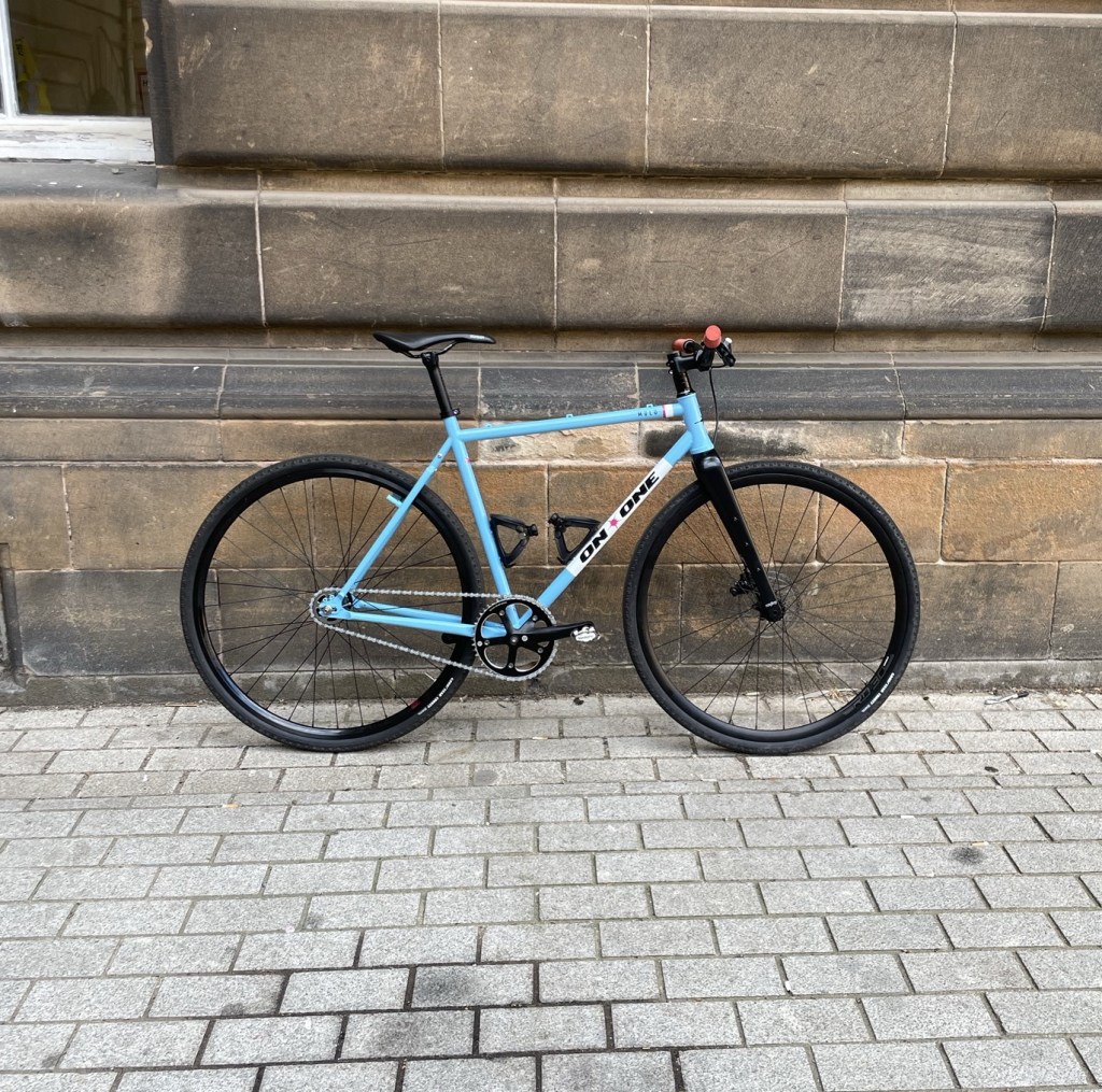 Blue fixed-gear bike leant against a limestone wall